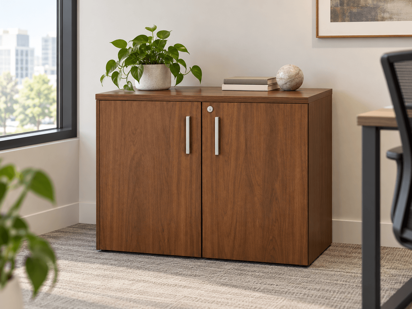 Armoire basse deux portes en noyer dans un bureau, avec plante et livres posés sur le plateau